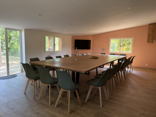 Salle de séminaire moderne au Domaine de Brise Bois avec grande table en bois, chaises noires et mur d'accent orange