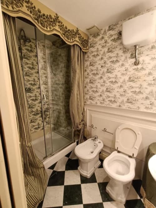 Bagno della Suite Magna Mater con doccia in vetro, due water, bidet e pavimento a scacchiera nell'appartamento hotel italiano