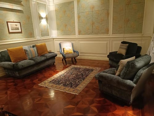 Elegant soggiorno della Magna Mater Suite con sedute grigie, tappeto ornato, carta da parati decorativa e pavimento in legno lucidato