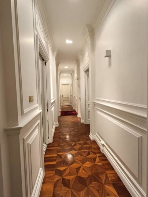 Elegante corridoio della Magna Mater Suite hotel in Italia con pareti bianche, modanature decorative, pavimento in legno e illuminazione incassata