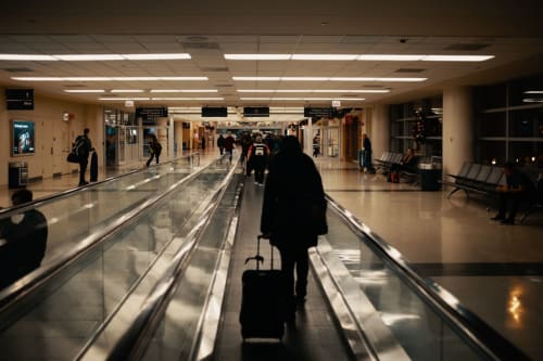 Viaggiatore con bagagli su una scala mobile in aeroporto diretto a Roma Imperial Suites