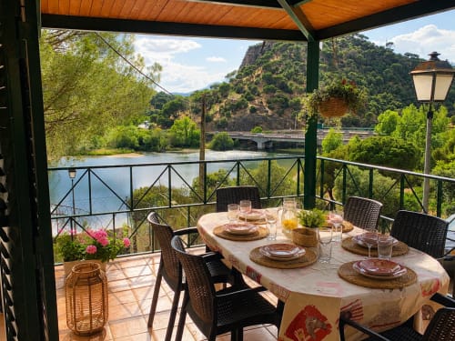 Comedor en terraza con vista al Lago Navas del Rey en Las Casitas de Noe, mesa preparada, vistas panorámicas y entorno boscoso