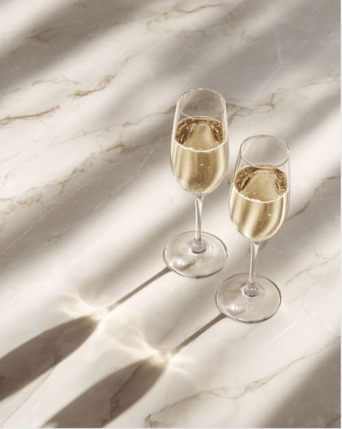 Deux flutes à champagne remplies de vin pétillant sur une surface en marbre à l'hôtel L'Escapade, Le Mans