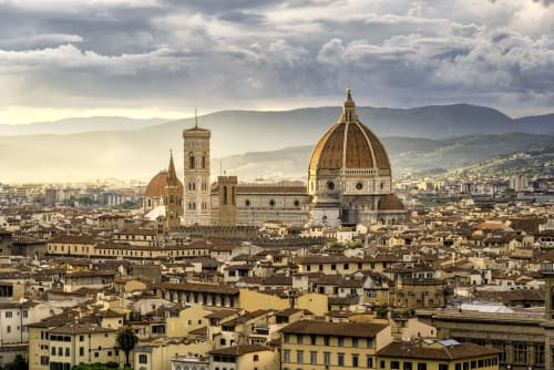 Florence Cathedral with golden dome overlooking terracotta rooftops and Tuscan hills