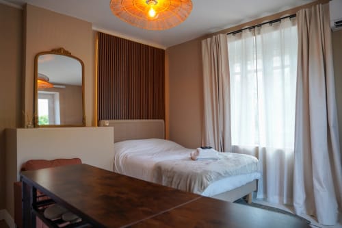 Chambre studio moderne au 1 Péraudel à Castres avec lit, bureau, miroir et vue sur le jardin par de grandes fenêtres