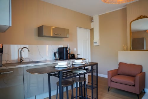 Studio moderne au 1 Péraudel à Castres avec cuisine, table à manger et fauteuil en terre cuite