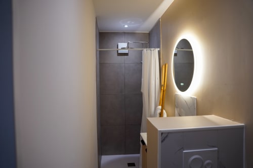 Salle de bains moderne avec miroir ovale lumineux, vasque en marbre et douche à l'italienne au Le 1 Péraudel à Castres