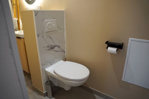 Salle de bain moderne avec toilettes blanches, cabine de douche à motifs marbre et porte-serviettes noir au 1 Péraudel à Castres