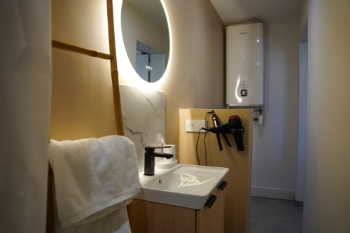 Salle de bain moderne du studio Le 1 Péraudel à Castres, avec miroir éclairant, lavabo blanc et équipements