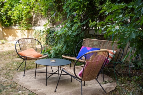Coin salon cosy du Le 1 Péraudel avec chaises en rotin, coussins colorés et murs recouverts de lierre à Castres