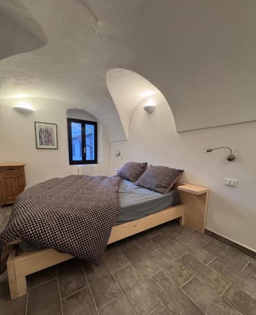Cozy bedroom with arched ceiling at Talking Stones Group, Dolceacqua, Italy - wooden bed with patterned bedding and ambient