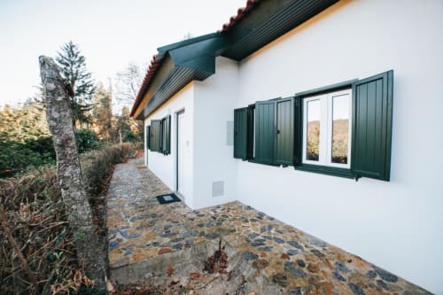 Bungalow branco moderno com persianas verdes e caminho de pedra no hotel Remote Care & Co em Braga, Portugal