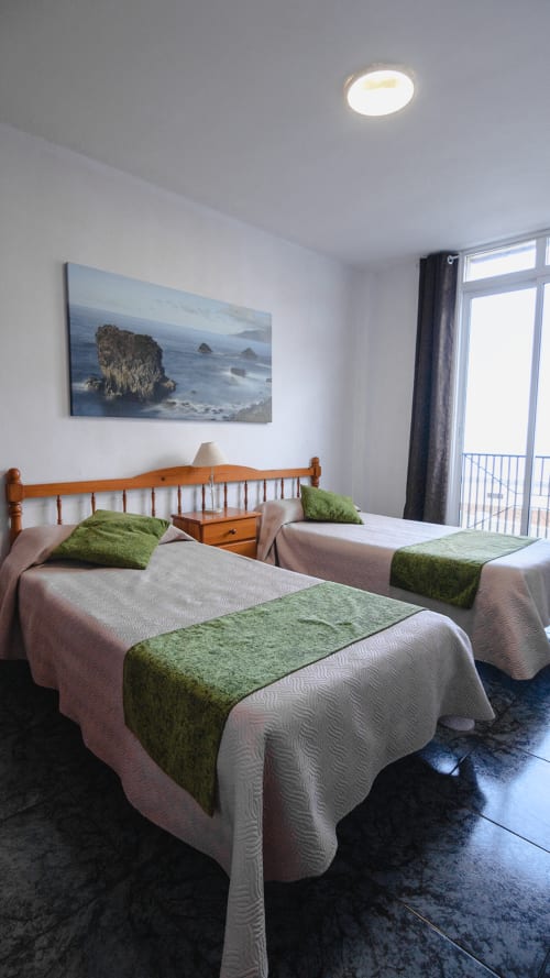 Luminoso dormitorio doble con vistas al mar en Apartamentos Jucar, Frontera, con camas de madera y arte de paisaje costero