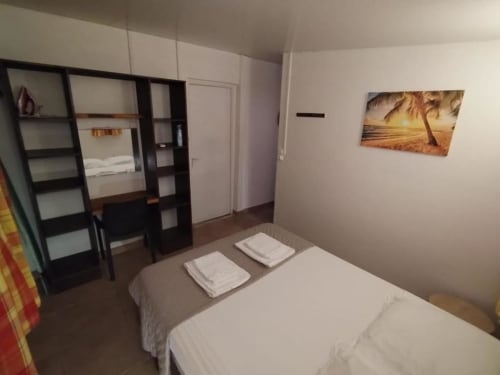 Chambre lumineuse avec lits jumeaux, étagères noires et artwork coucher de soleil tropical à la Sunshine Conciergerie