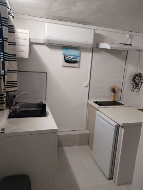 Kitchenette moderne à l'appartement Sunshine Conciergerie, Fort-de-France, équipée d'armoires blanches, cuisinière, évier et