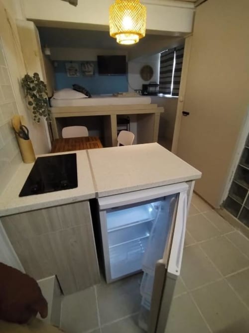 Petite cuisinette équipée à l'auberge Sunshine Conciergerie avec plaque de cuisson, réfrigérateur et coin repas à Fort-de-France