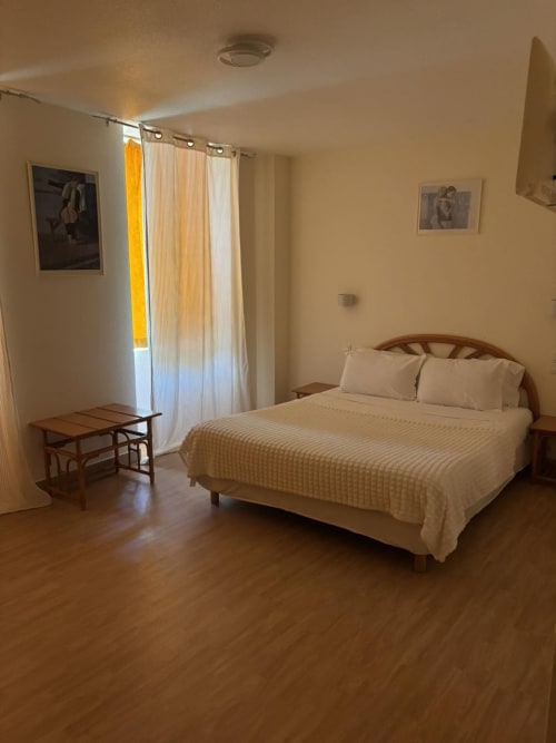 Geräumiges Doppelzimmer im Hôtel Du Rocher in Le Caylar mit Queensize-Bett, Holzmöbeln und Stadtblick von der Terrasse
