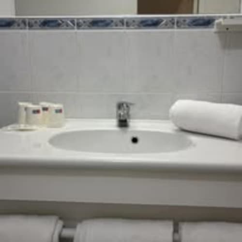 Makelloses weißes Badezimmerbecken mit Armatur, Handtüchern und Toilettenartikeln im Hôtel Du Rocher in Le Caylar