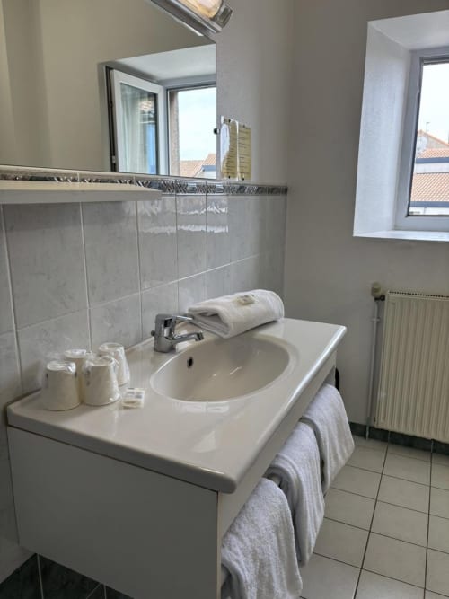 Modernes Badezimmer im Hôtel Du Rocher mit weißem Waschbecken, Spiegel, Fliesenrückwand und Ausstattung in Le Caylar