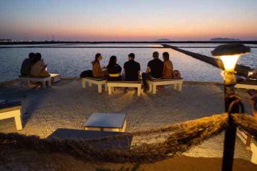 Gruppo che gode del tramonto in riva al mare a Villa Giulia sul Mare, lido di Marausa, Sicilia