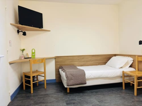 Barrierefreies Zimmer im Hôtel Du Rocher in Le Caylar mit Einzelbett, Holzmöbeln, Fernseher und Schreibtisch