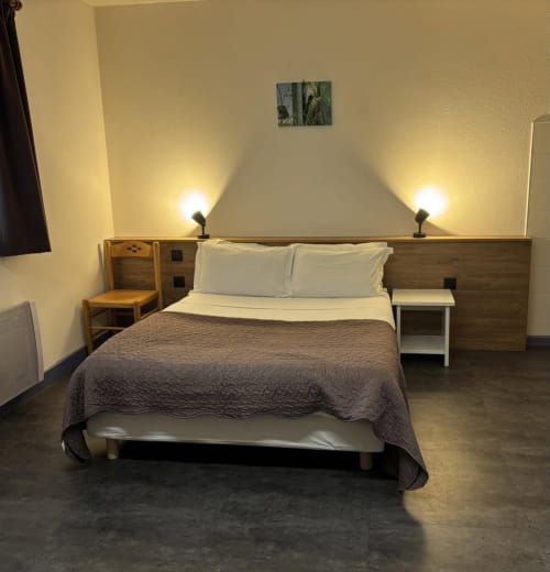Modernes barrierefreies Hotelzimmer im Hôtel Du Rocher mit Queensize-Bett, Holzkopfteil, warmer Beleuchtung und zeitgenössischem Design
