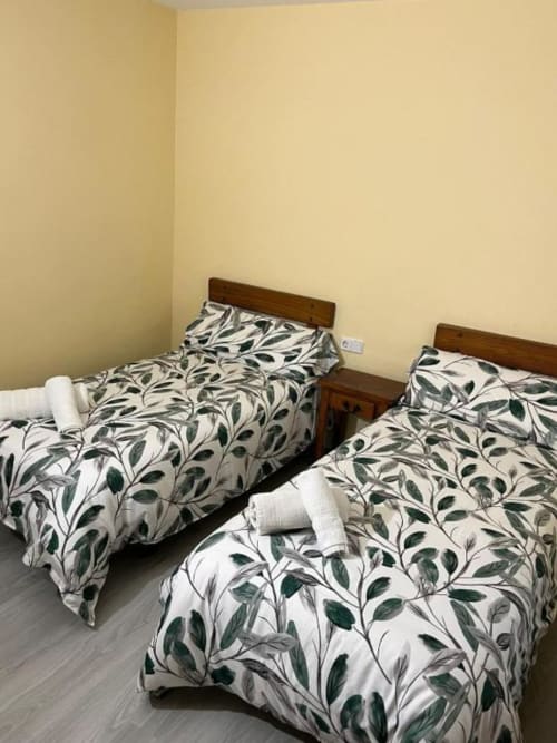 Habitación doble en Hostal Restaurante El Encuentro en Barraco con dos camas individuales y ropa de cama con estampado de hojas