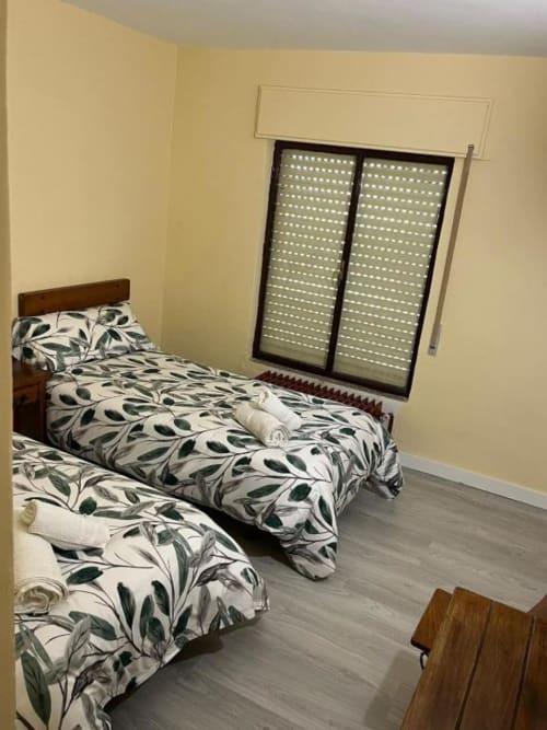 Habitación doble en Hostal Restaurante El Encuentro en Barraco con ropa de cama de hojas verdes y contraventanas