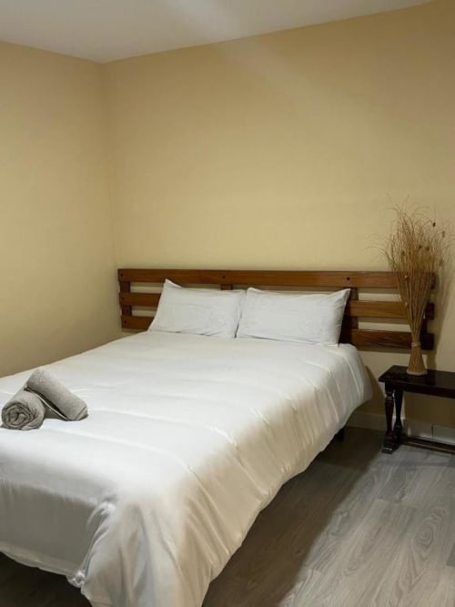Habitación doble limpia en Hostal Restaurante El Encuentro en Barraco con ropa de cama blanca, cabecero de madera y decoración moderna