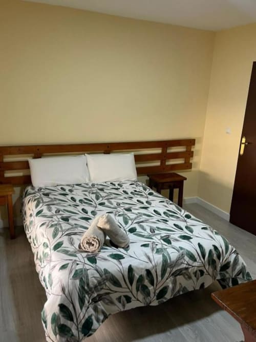 Habitación doble con ropa de cama estampada de hojas en el Hostal Restaurante El Encuentro de Barraco, España