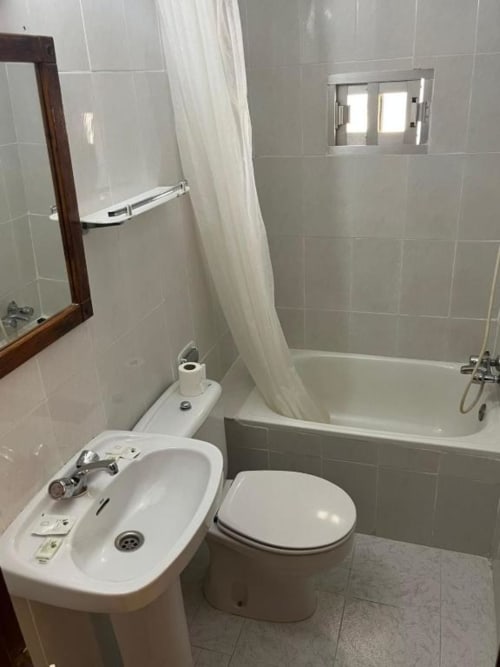 Baño moderno con inodoro, lavamanos y bañera con cortina de ducha en Hostal Restaurante El Encuentro, Barraco
