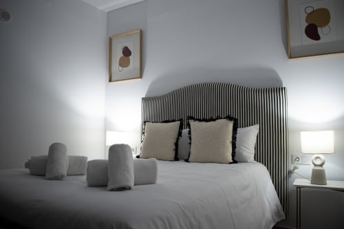Dormitorio moderno en Apartamento Diocles Centro, Mérida con cabecera a rayas, ropa de cama blanca y decoración contemporánea