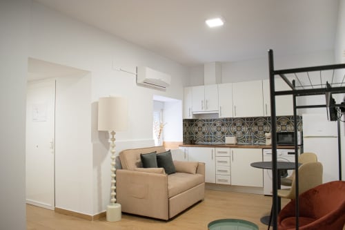 Estudio moderno en Mérida con sillón beige, cocina blanca, backsplash con patrón y cama tipo loft.
