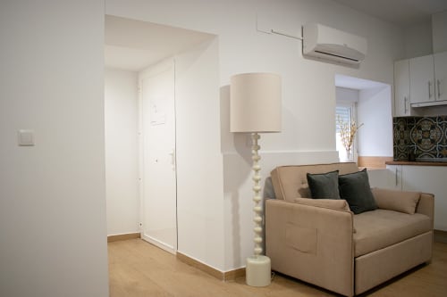 Moderna sala de estar del Apartamento Diocles Centro, Mérida con sofá beige, lámpara crema y aire acondicionado