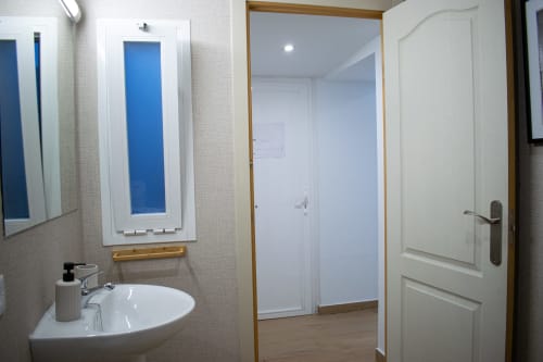 Baño moderno en Apartamento Diocles Centro, Mérida con lavamanos blanco, espejo y acceso al pasillo