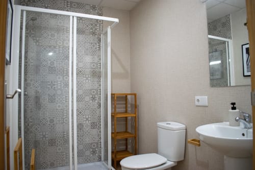 Baño moderno en Apartamento Diocles Centro, Mérida con ducha, inodoro, lavabo y estantería de madera