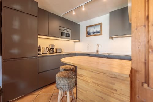 Cuisine moderne de l'appartement Cosyarc à Arc 1800, avec mobilier marron, plan de travail en bois et décoration montagne