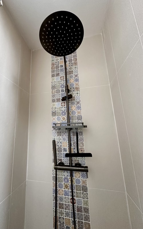 Modern black rainfall showerhead with geometric tiled accent wall in La Recreation cottage bathroom, Missillac