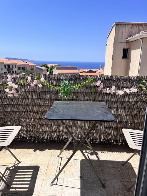 Terrasse avec vue sur mer à Casa Monica à Cargese, table de dining et fleurs roses dominant la Méditerranée