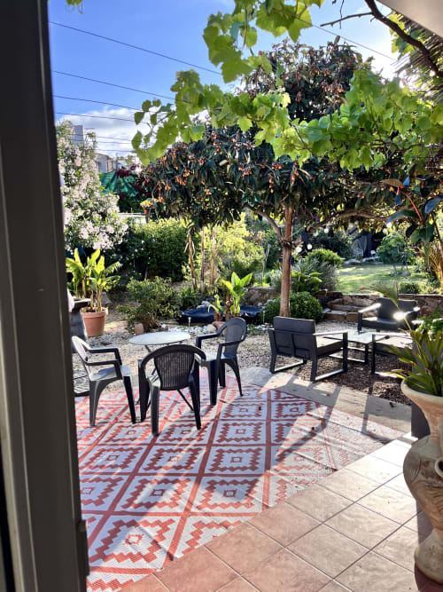 Terrasse verdoyante à Casa Monica Cargese avec coin détente, tapis géométrique et fruitiers sous ciel bleu