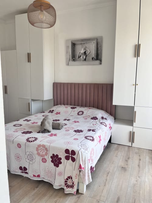 Chambre moderne à la Casa Monica à Cargese avec lit queen-size, parure florale, tête de lit mauve, penderies blanches et luminaire suspendu