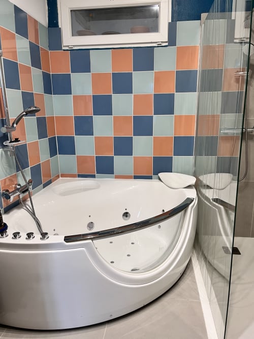 Baignoire jacuzzi d'angle luxueuse avec carrelage coloré dans la suite vue mer L.O.V.E de Casa Monica, Cargèse