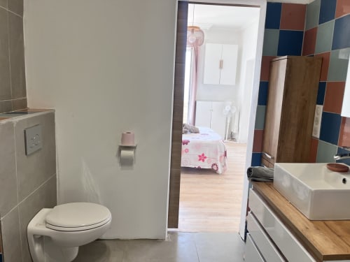 Salle de bain moderne de la Casa Monica B&B à Cargese, avec toilettes, lavabo et vue sur la chambre avec vue mer et carrelage coloré