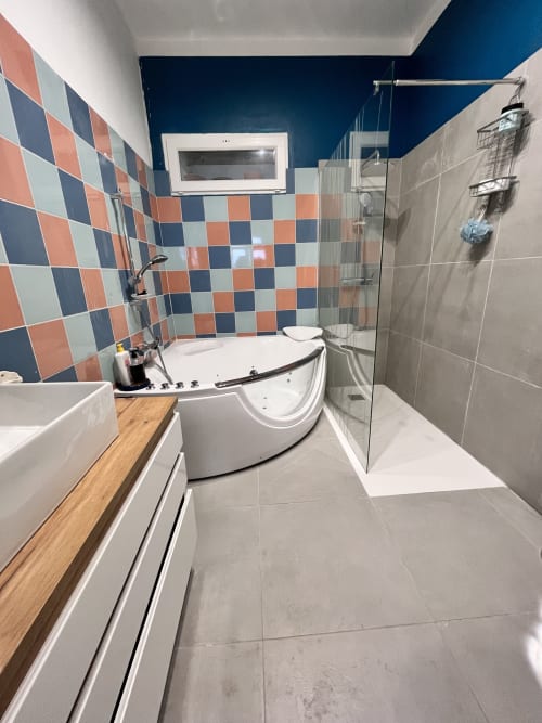 Salle de bain moderne à Casa Monica avec baignoire jacuzzi d'angle, douche spacieuse, carrelage à motifs colorés et mur d'accent bleu