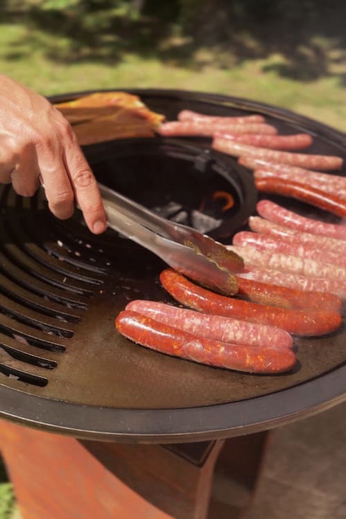 Personne faisant griller des saucisses au barbecue extérieur de la Maison Mansel, Mesnil-en-Ouche