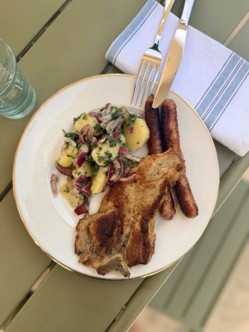 Assiette petit-déjeuner de la Maison Mansel avec salade de pommes de terre aux herbes, bacon, saucisses et toast