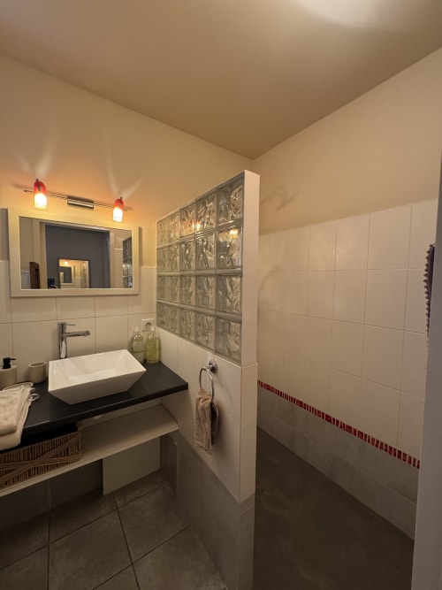 Salle de bains moderne du Domaine d'Olga à Aniane avec vasque blanche, douche en briques de verre et éclairage ambiant