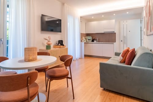 Modern open-plan living area in Pescara INN Family Suite with dining table, sofa, kitchen, and wall-mounted TV