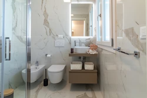 Modern marble bathroom in Pescara INN Family Connecting Suite with white fixtures, vanity sink, and accessible design