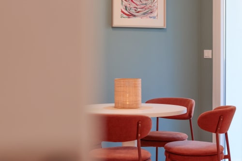 Modern dining area in Pescara INN Family Connecting Suite with round wood table, red chairs, and orange pendant lamp